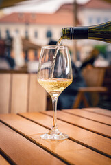 Pouring white wine into a glass on a wooden table