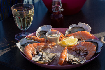Seafood tasting plate as promo on the oysters' farm in the South of France. Traditional Mediterranean seaside lunch or dinner - white wine, shrimp, oysters, aioli sauce, lemon, and vinegar.