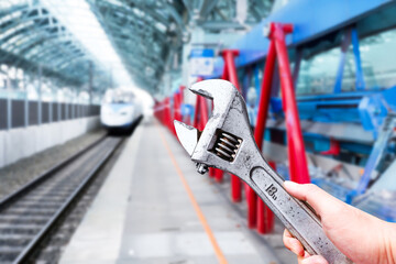 High speed train maintenance concept , Mechanic hand holding a adjustable wrench with high speed train station blurred on background