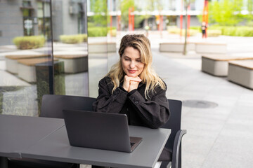 Businesswoman working with laptop in outdoor cafe. Corporate blog