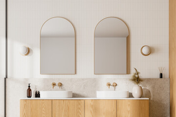 Modern bathroom with wooden cabinets, dual sinks, and arched mirrors, light background....