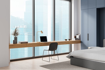 Modern workspace with wooden desk, laptop, and chair by large windows overlooking cityscape, in a minimal blue and gray bedroom. Light, contemporary design concept.  3D Rendering