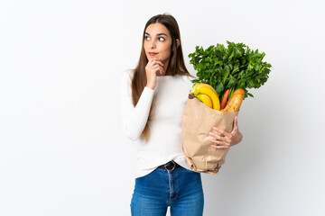 Young caucasian woman buying some food isolated on white background thinking an idea while looking...