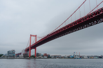 Red suspension bridge over calm urban waterway