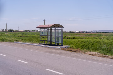 A bus stop is located on a road with a lot of grass