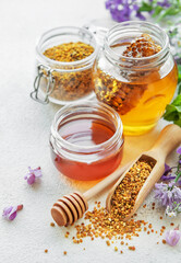 Raw organic bee pollen and honey in jars.