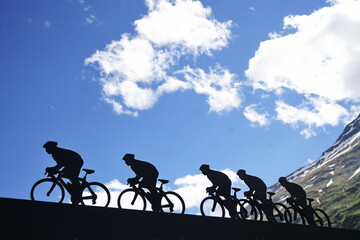 Lanslebourg-Mont-Cenis , France - June 20 2024: A group of cyclists tackle the steep Alpine climb in the back light.