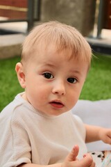 A cute little boy with black eyes is looking at the camera