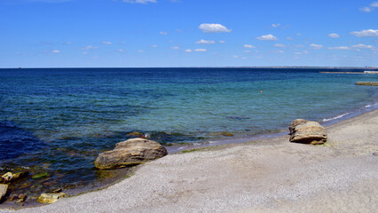 A picturesque seascape overlooking the blue sea, rocks and stones on a bright sunny day. The waves break against the rocks. the stone lies on the beach. coastline, leisure concept, tourism, vacation