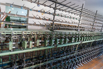 Naklejka premium A large machine with many spools of thread hanging from it. The machine is green and has a lot of metal parts