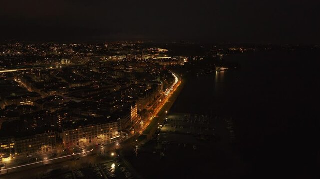 Serene nightscape of Geneva from above, showcasing the beautifully illuminated waterfront and urban expanse