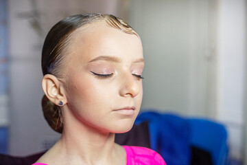 stylist applying eyeliner to a happy girl's eyelids before a ballroom dancing tournament. Fashion &...