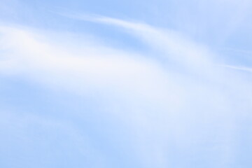 A single-engine plane soaring above a clear blue sky with scattered white clouds, offering a serene and peaceful atmosphere