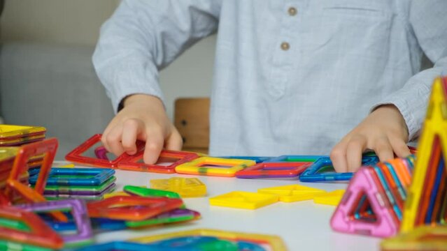 Child playing with magnetic constructor, hands close-up.