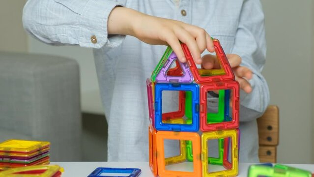 Child playing with magnetic constructor, hands close-up.