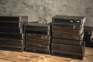 Many old satellite receiver boxes that are damaged. Damaged, unusable, stacked in the room