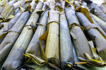 Fototapeta premium Close up of cylindrical rice cake cooked with banana leaves. Indonesian traditional food called Lontong or Ketupat. Rice rolled in banana leaves and boiled.