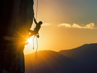 Silhouette of a Climber Scaling a Mountain at Sunset