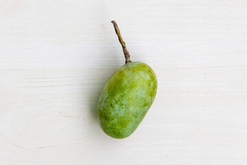 A fresh raw green mango on a wooden background. Top view.