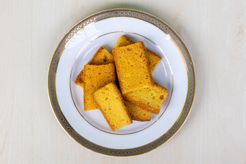 Tasty dry cake rusk biscuits on a white plate on wooden background. Top view.