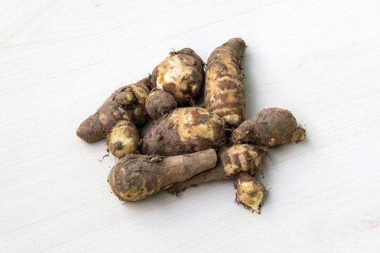 Taro root or kochur mukhi isolated on light white wooden surface. Fresh vegetable.