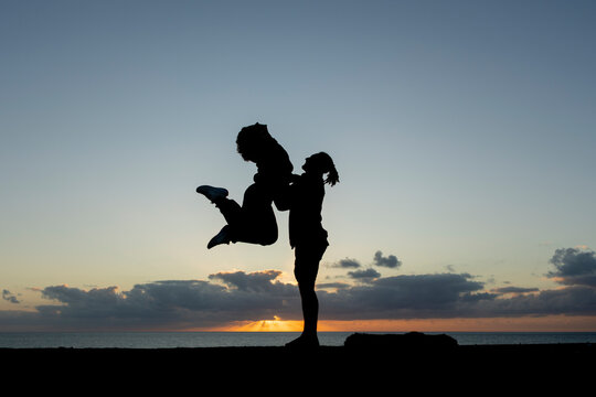 Silhouetted dancers perform against a vibrant sunset