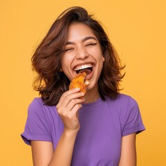 Young Woman Enjoying Delicious Fried Chicken Against a Yellow Background