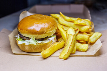 Hamburger - American cheese burger with Golden French fries on craft paper close-up 