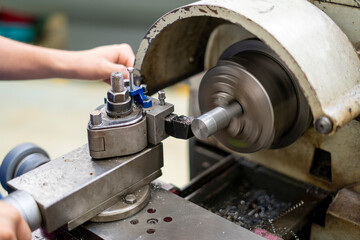 A worker working on an old lathe machine in a workshop