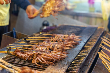 The photo showcases a mouthwatering grilled squid, cooked to perfection over an open flame. The golden-brown exterior glistens under the smoky aroma of the barbecue