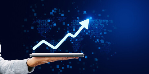 A hand holding a tablet displaying a graph arrow soaring upwards, representing growth, against a digital world map backdrop