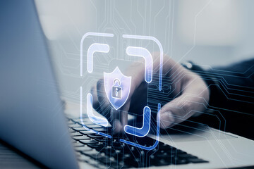 A person working on a laptop with a digital security hologram concept overlay on a blurred background, creative cyber security theme
