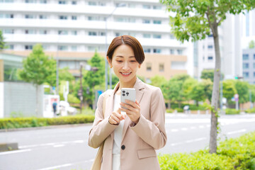 Fototapeta premium 外でスマートフォンを使うビジネスウーマン