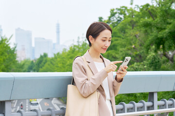 Fototapeta premium 外でスマートフォンを使うビジネスウーマン