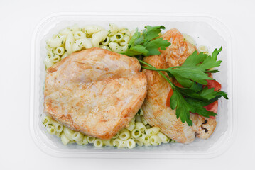 Fried chicken fillet with a side dish of pasta. Delicious meat breakfast in a container.