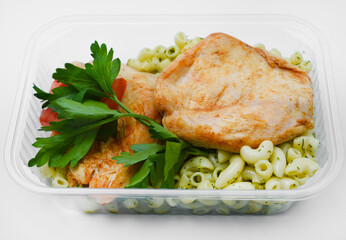 Fried chicken fillet with a side dish of pasta. Delicious meat breakfast in a container.