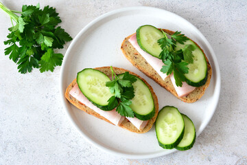 a plate of sandwiches with parsley, ham and cucumber top view