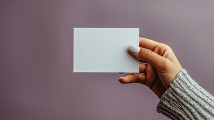 A clean and simple image showing a hand presenting a blank, white card against a smooth, purple background, ready to be customized with text or design.
