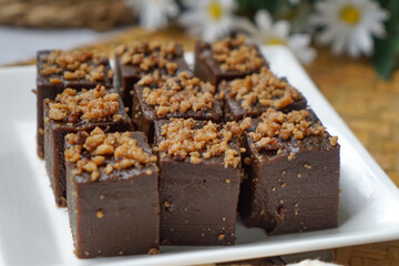 Kuih kole kacang, a steamed Malaysian cake, made with fried green bean flour, coconut milk, and palm sugar.  The decoration of the cake is from coconut oil grease or residue. Selective focus.