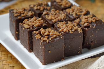 Kuih kole kacang, a steamed Malaysian cake, made with fried green bean flour, coconut milk, and palm sugar.  The decoration of the cake is from coconut oil grease or residue. Selective focus.
