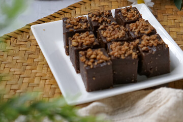 Kuih kole kacang, a steamed Malaysian cake, made with fried green bean flour, coconut milk, and palm sugar.  The decoration of the cake is from coconut oil grease or residue. Selective focus.