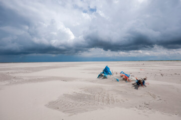 Cold sunny weather with storm and heavy clouds on the beach of the island of Schiermonnikoog, in June 2024  ,The Netherlands.Waste on the beach