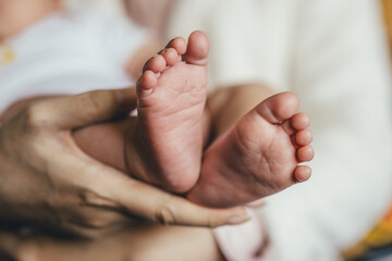 Close up of newborn baby feet. Mother holding her baby in her arms.