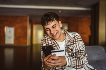 Young boy stand and buy online on mobile phone with credit card
