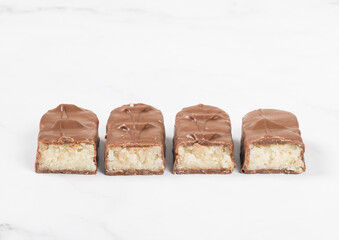 Candy bar with coconut pulp, in milk chocolate. White background. Close-up.