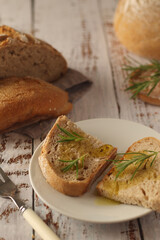 A loaf of rye bread with oil and rosemary in rustic style