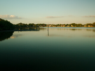 Wide view of Coffee Pot Park bayou in St. Petersburg, Florida with blue water and sky. Wood dock on the left side on a sunny day. Near sunset with reflections. Looking south on a calm day in  St. Pete