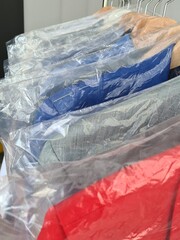 Obraz premium Stack of Cleaned and Wrapped Suits on Hangers in a Dry Cleaning Store