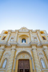 facade of catholic church with white patterns on yellow wall and saints