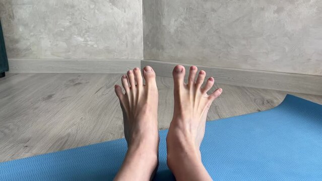 Close up of feet doing flexibility exercises on a blue yoga mat. Ideal for yoga, fitness, and wellness content